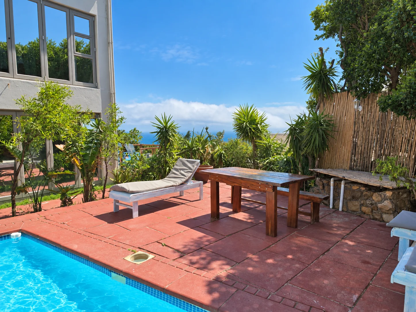 Pool corner with an ocean glimpse through the plants