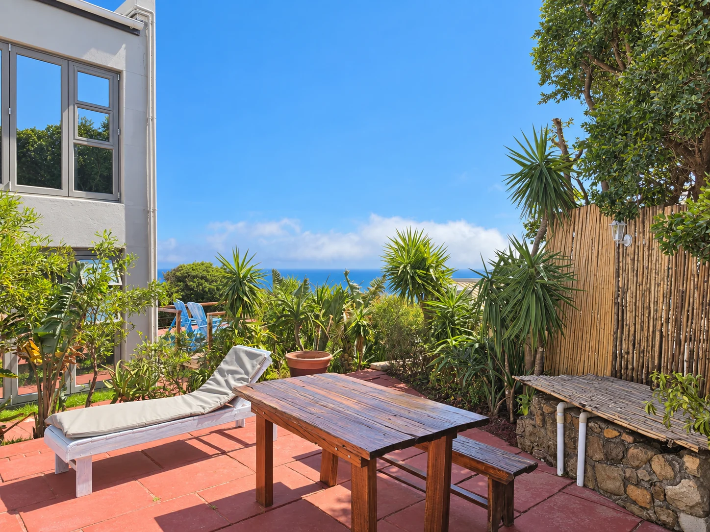 VistaBlu terrace with an ocean glimpse through greenery